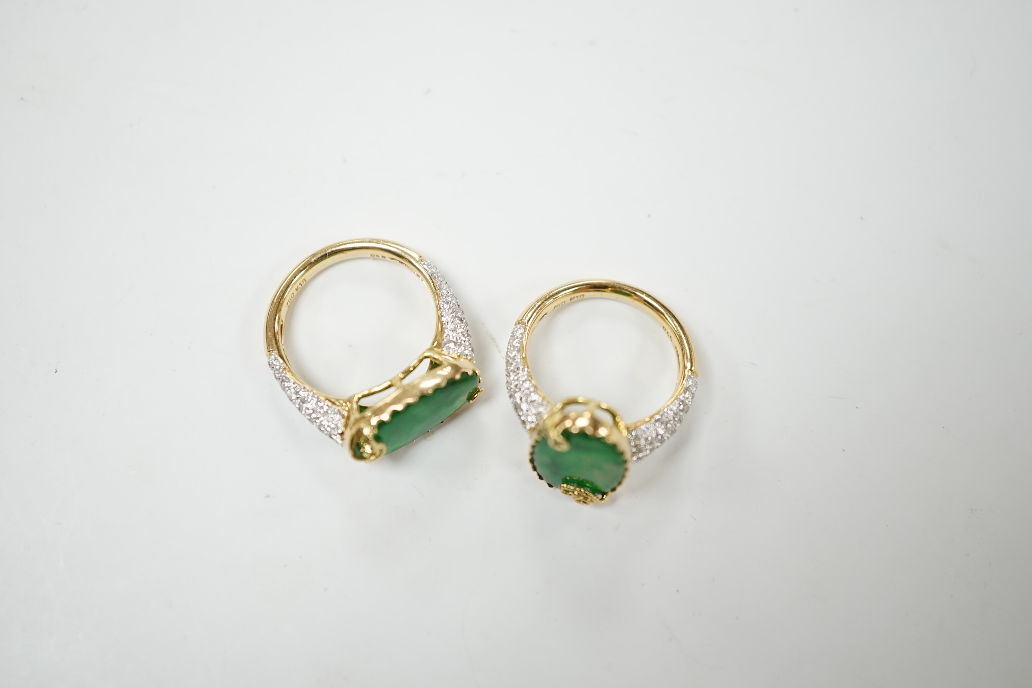 Two similar modern 18k and oval jade set dress rings, with diamond chip set shoulders, sizes K & L, gross weight 9.9 grams. Condition - good